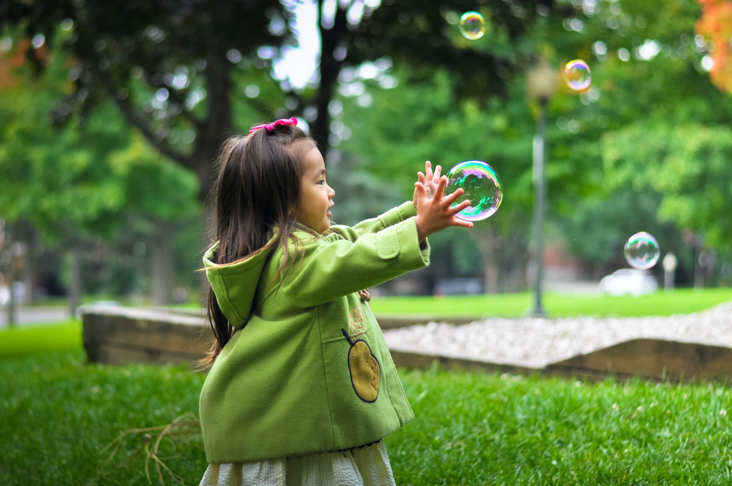 Child of preschool age enjoying blowing bubbles outdoor